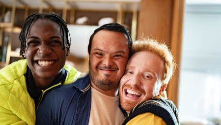 Portrait of a disabled young man and his friends embraced at home